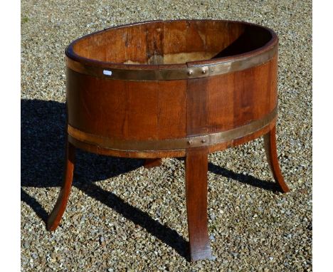 A late Victorian/Edwardian mahogany oval planter of coopered form raised on four long staves to form the legs, mounted with b