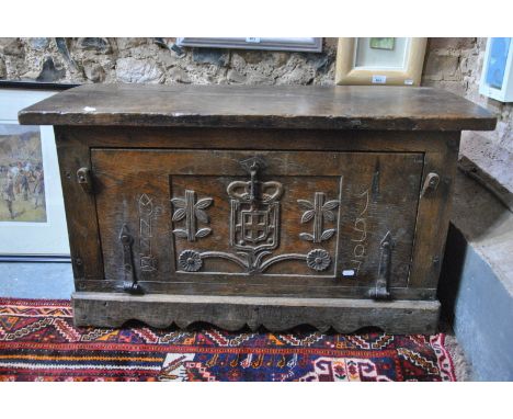 A small oak plank hall chest trunk, the rectangular top over a hinged panel carved with an armorial device.