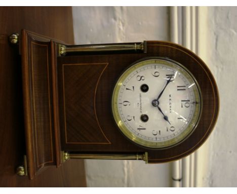 An Edwardian inlaid mahogany and brass mantel clock, the arched cased with brass pillars and ball feet enclosing an enamel di