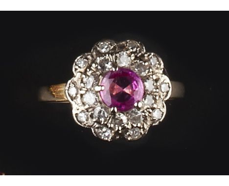 A RUBY AND DIAMOND CLUSTER RING, the circular mixed-cut ruby claw set within a tiered double row border of brilliant and sing