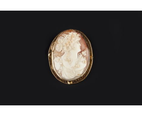 AN OVAL SHELL CAMEO BROOCH, carved to depict the portrait profile of a bacchante, with fruiting vines to her hair and gown, i