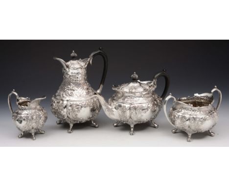 AN EDWARDIAN FOUR PIECE SILVER TEA SET consisting of an ornately chased teapot with scroll and foliate decoration, four cabri