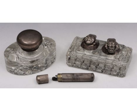 A CUT GLASS AND SILVER MOUNTED INKWELL, oval shaped with a domed hinged lid, 9.5cm wide; a further inkwell with silver mounts