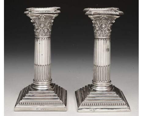 A PAIR OF VICTORIAN SILVER DWARF CANDLESTICKS standing on square stepped bases and with corinthian columns, 15cm high, London