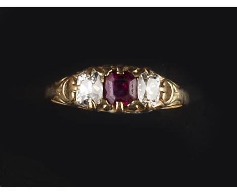 A RUBY AND DIAMOND THREE STONE RING, the octagonal step-cut ruby framed by two cushion-shaped diamonds, to a pierced and engr