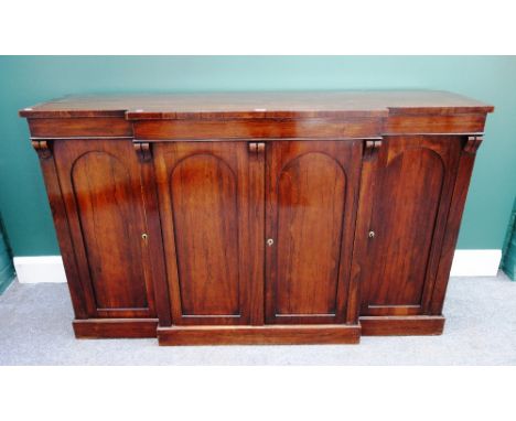 A mid 19th century rosewood breakfront side cabinet, the four arch top panel doors, on plinth base, 153cm wide.