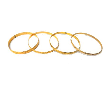 Four circular gold bangles, each with scroll engraved decoration, mostly detailed 18 K, (some marks indistinct), combined wei