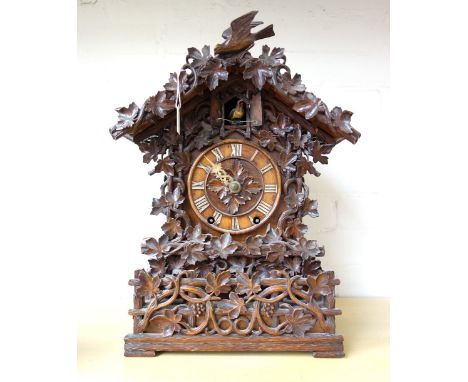 A Black Forest carved walnut or Linden wood mantel clock, late 19th century, with automaton cuckoo within an ornately carved 