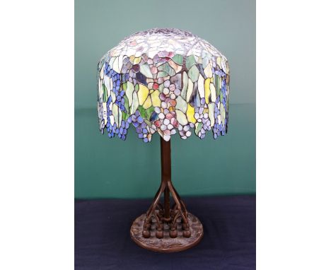 A bronze and coloured glass Tiffany style table lamp, late 20th century, with a foliate coloured shade over a naturalistic br