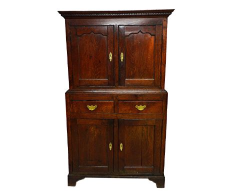 An 18th century oak side cupboard, the diamond carved cornice over a pair of shaped panel doors, two short drawers and a furt