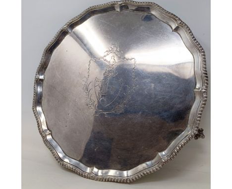 An 18th century silver salver, of shaped circular form, the centre with engraved decoration having a crest above a shield, wi