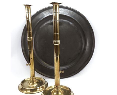 A pair of tall 18th century brass ejector candlesticks, height 44cm, and an 18th century pewter charges, 46cm diameterCandles