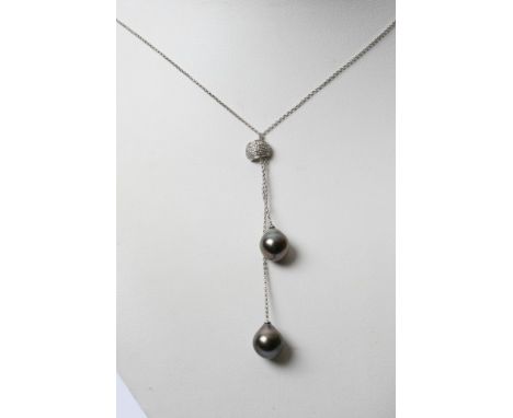 A white gold and black pearl necklace with a small semi circular clip inset with diamonds 