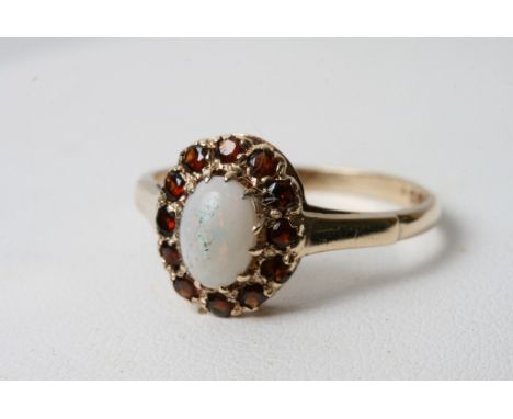 A 9ct gold ring set with a central opal, flanked with garnets 