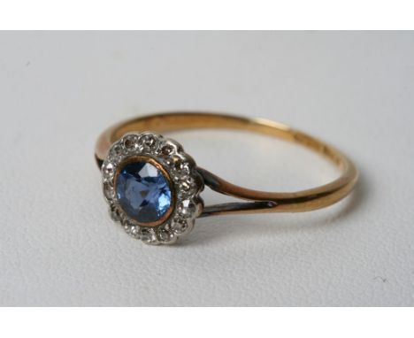 A gold ring set with light blue sapphire and diamond chip surround