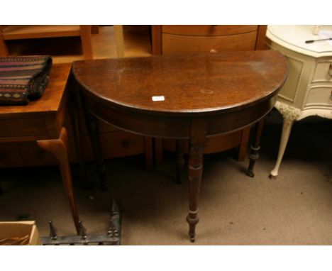 An oak semi circular card table, turned legs on ceramic casters 