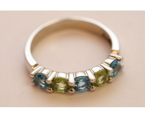 A 14ct white gold ring set with alternating blue topaz and peridot