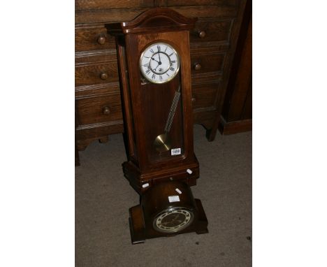 A modern wall clock with a visible pendulum and an oak mantel clock (2)
