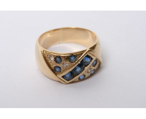 A 14ct gold blue sapphire diamond set ring, the band set with nine blue sapphires and four diamonds. 