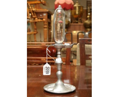 A pewter whale oil lamp clock, the glass reservoir enclosed within a pewter strap embossed with hour scale and oil burner to 