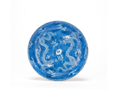 A BLUE AND WHITE RESERVE-DECORATED 'DRAGON' DISHKangxiThe interior painted with two dragons coiled in flight around a single 