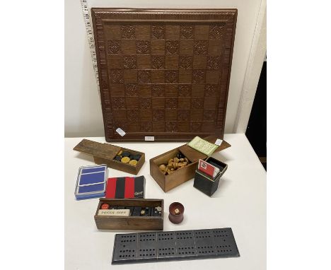 A wooden carved chess board and a selection of game pieces including chess, dominoes, draughts and dice 