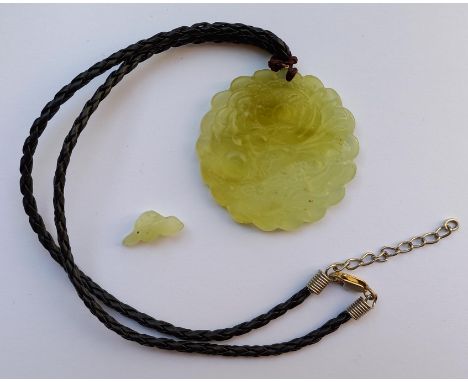 Jade Schnitzerei. Als Collier. Wohl China alt.46 mm Durchmesser, 8 mm dick. Lederband später. Und eine kleine Jadeschnitzerei