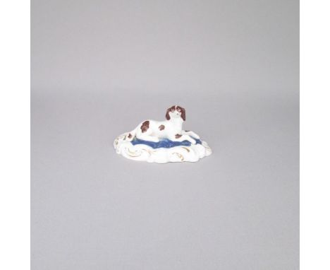 An English porcelain model of A Spaniel laying on a blue , white and gilt decorated baseDate: Circa 1840   Size: 9cm diameter