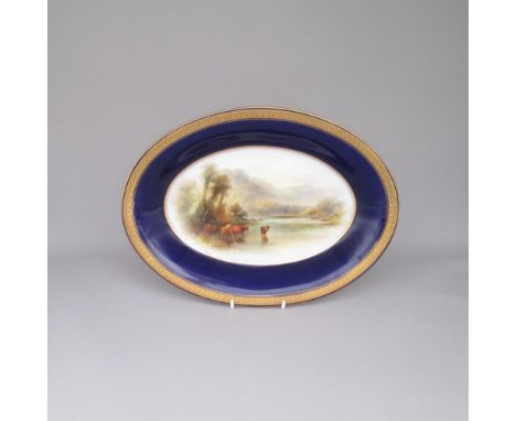 A Royal Worcester Oval Dish  Cobalt blue ground and raised gilding  The centre painted with highland cattle  standing in a lo