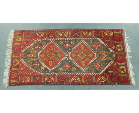 An Eastern fringed rug, the centre panel with repeating designs and with line border and fringed ends.   Width 102 cm, length