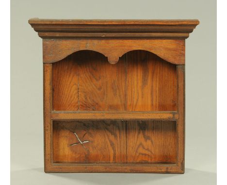 A 19th century oak small hanging shelf unit, with moulded cornice above a shaped apron and two shelves.  Width 58 cm. 