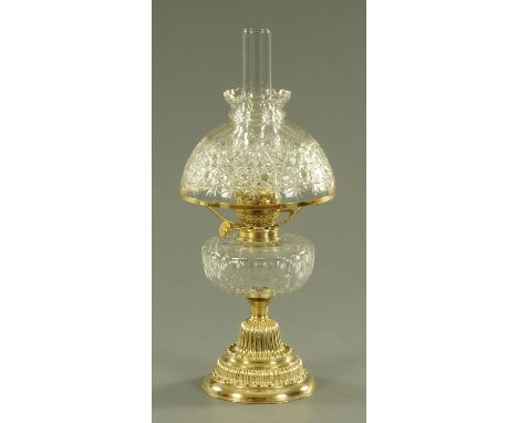 A brass and cut glass oil lamp, early 20th century, cut glass shade and reservoir upon an embossed and gadrooned stepped bras