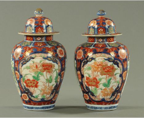 A pair of Japanese Imari vases and covers, circa 1880/90, decorated throughout with panels of blossoming peony between watery