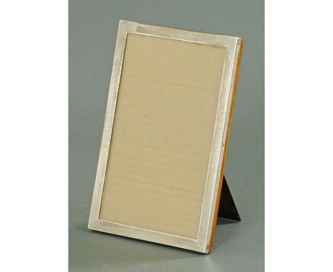 A silver picture frame, Sanders and Mackenzie, Birmingham 1927, with engine turned decoration upon an oak mount with easel su