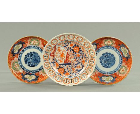 A pair of Japanese Imari plates, late 19th century, with under glazed blue peony framed by spuming waves and with a blood red