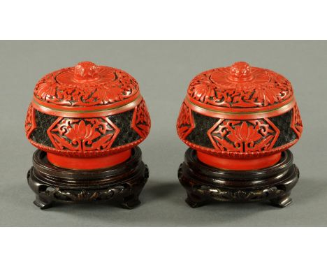 A pair of Chinese cinnabar lacquer bowls and covers, circa 1970, each with carved lotus panel against a black key ground and 