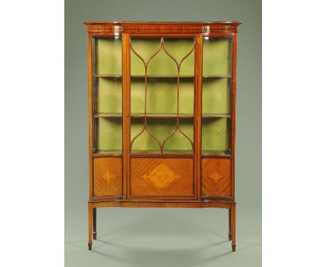 An Edwardian mahogany display cabinet, with breakfront and single glazed door enclosing shelves and all raised on tapered leg