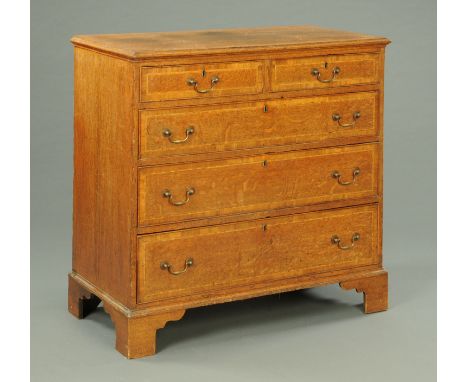 A George III oak and mahogany crossbanded chest of drawers, with moulded edge above two short and three long graduated drawer