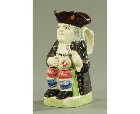 A Staffordshire pearl ware Toby jug, late 18th/early 19th century, decorated in prattware colours modelled seated holding a f