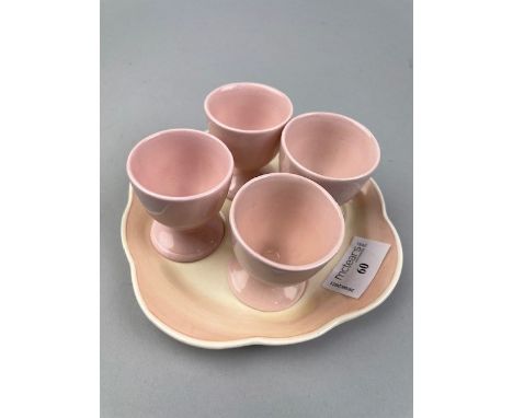 SUSIE COOPER EGG CUP STAND, along with four egg cups, in a pale pink and beige palette