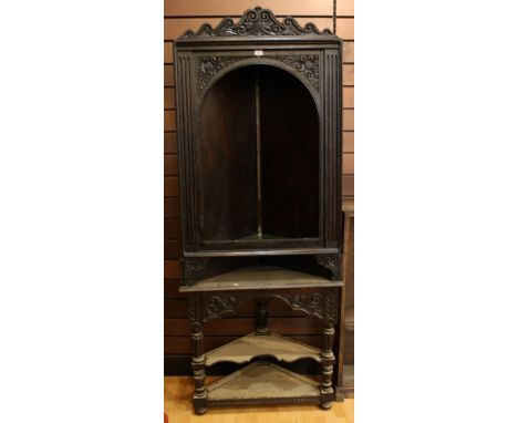 A 18th century dark oak open front floor standing corner cupboard, carved top, open shelf base