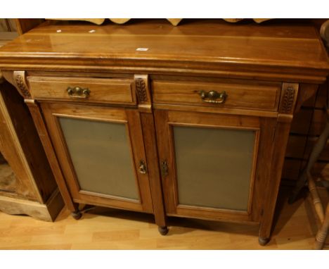 A 20th century sideboard, oversailing rectangular top above a pair of frieze drawers and two glazed doors enclosing a shelf