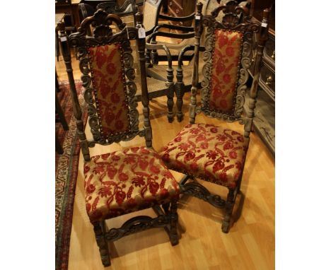 A pair of Spanish Colonial Revival hall chairs, each with an arched cresting rail carved with shells and acanthus, studded re