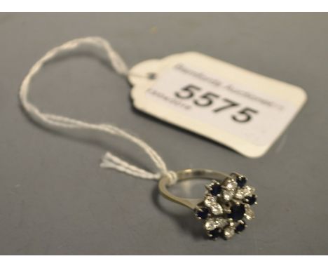 A diamond and sapphire cluster ring, stepped spiralling floral crest, set with six pairs of round brilliant cut diamonds, and