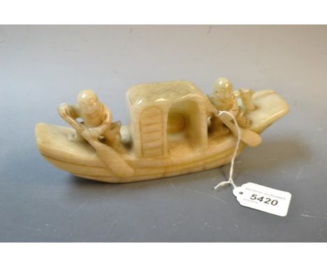 A carved jade boat, two figures aboard.