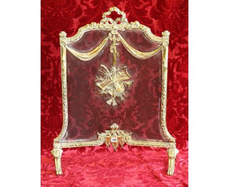 19th century brass and mesh fireguard with applied music instrument decoration, on scroll feet.