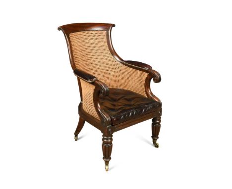 A Regency mahogany library bergere, with curved back, lapit carved arms, leather upholstered arm rests and buttoned leather s