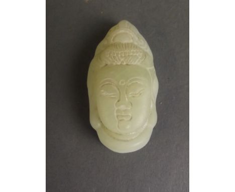 A Chinese light green jade pendant carved in the form of Quan Yin's face, 1½'' long