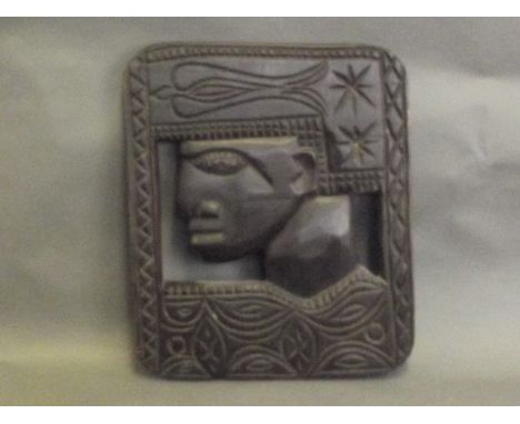 A carved African panel depicting a face, 14'' x 12''