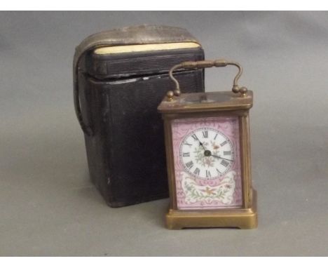 A brass carriage clock with pink ground ceramic panels painted with birds and flowers, in a leather carrying case, 6'' high